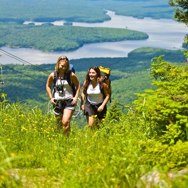 two women hiking in the foreground with a lake in the background